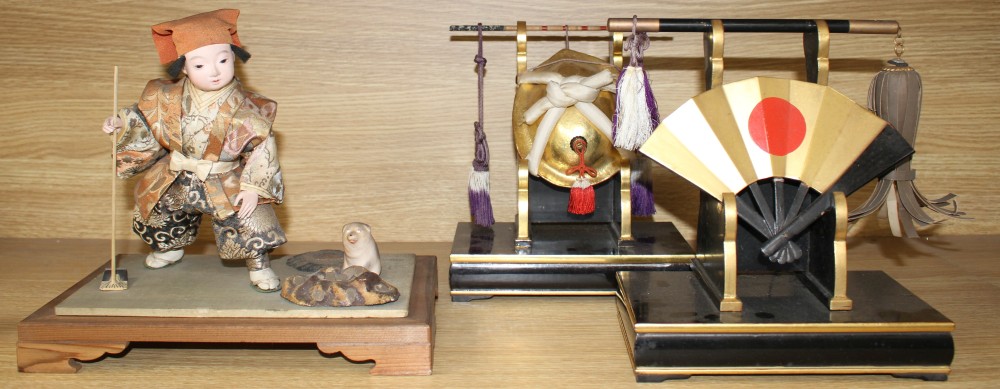 A Japanese late Meiji period composition and fabric figure of a boy farmer holding an adze with puppy seated nearby, mounted on display